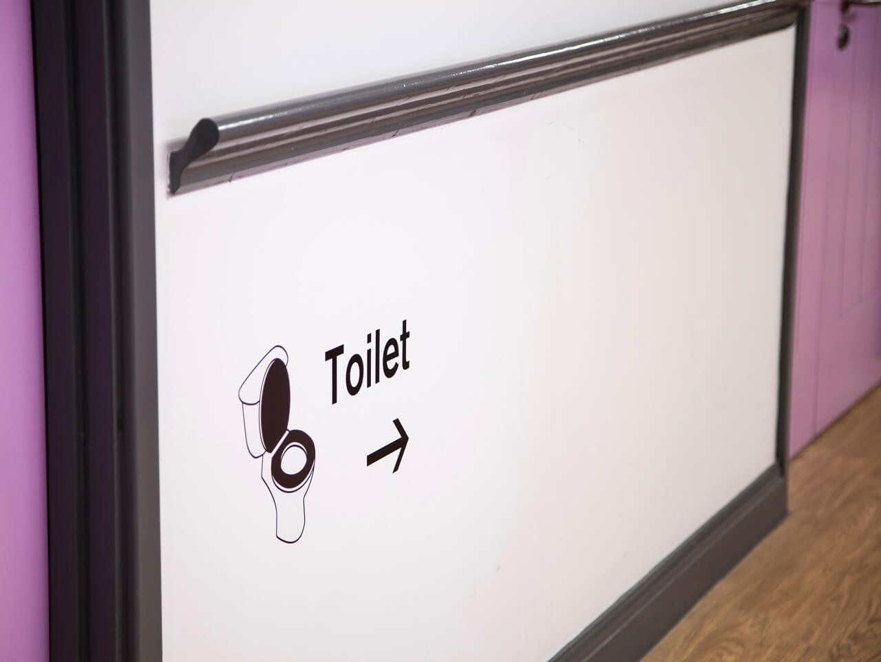 Dementia friendly signage for toilets at Haven Court with pictogram and directional arrow