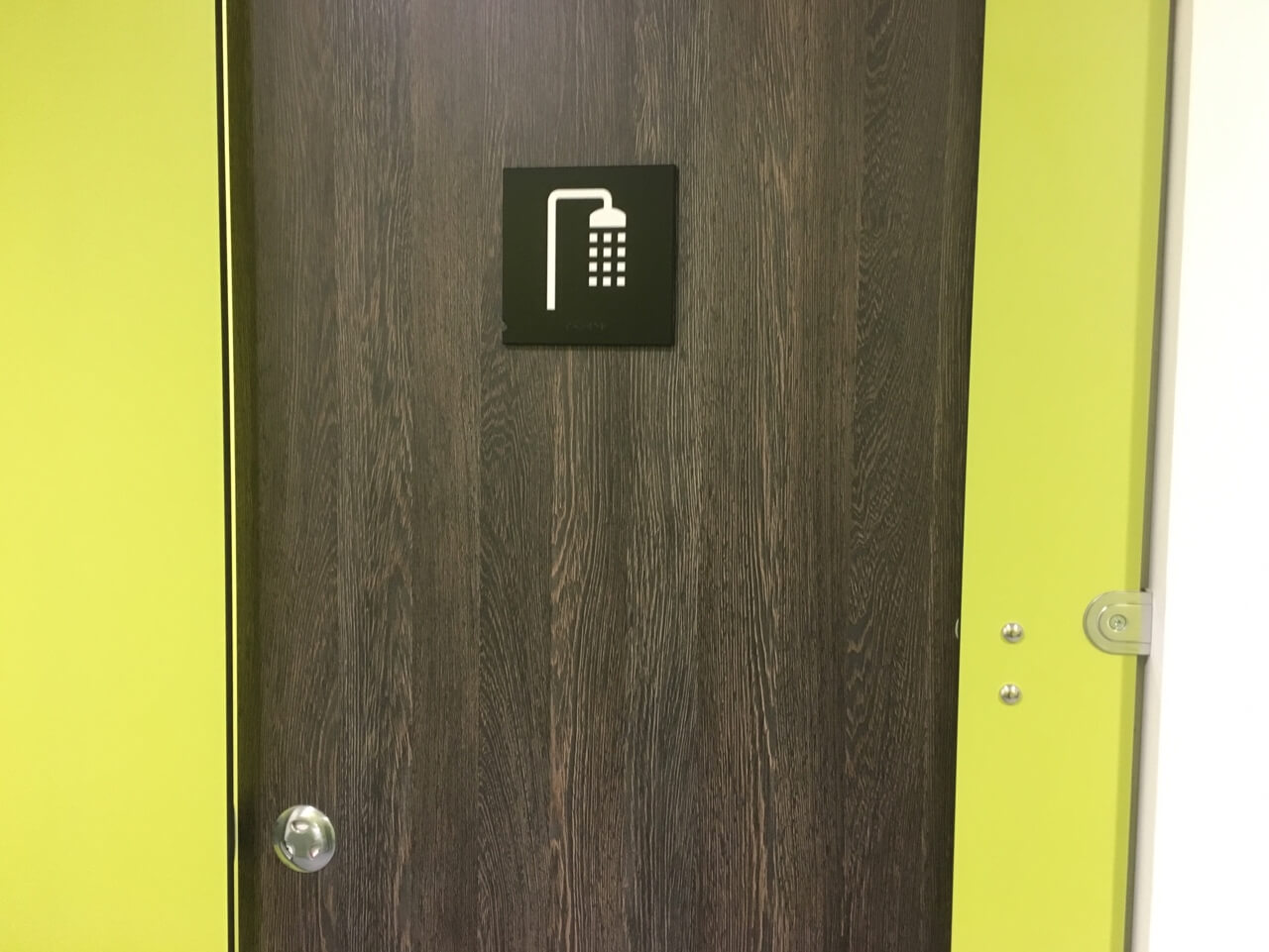 A sign showing a shower icon on the entrance door to the shower room